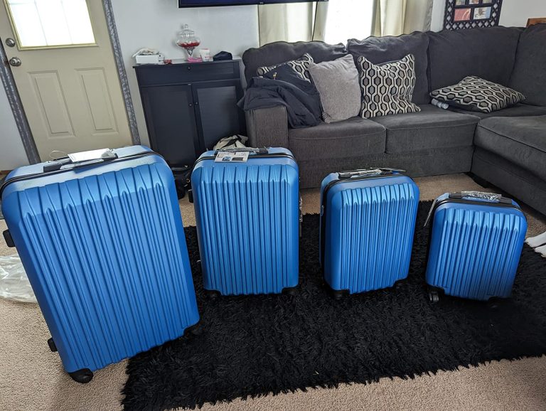Apelila 4-piece vertical stripe luggage set in blue displayed in a living room, showing 28”, 24”, 20” and 16” suitcases.