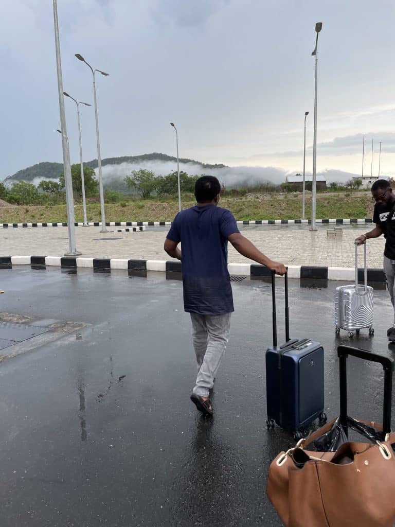 LEVEL8 Road Runner Carry-On Review: A Smart Tech Travel Suitcase 8 A traveler pulling the LEVEL8 Road Runner Carry-On across a wet pavement outdoors, demonstrating its smooth spinner wheels in rainy conditions.