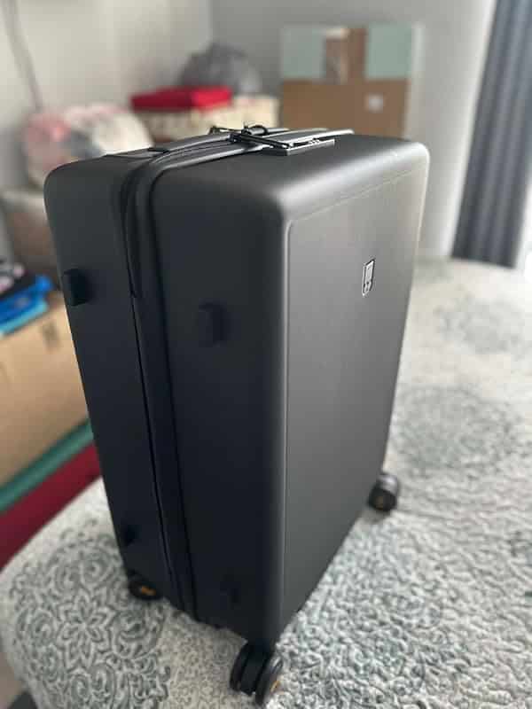Level8 Textured Luggage Set Review: Durable & Stylish Travel 6 Level8 Textured carry-on standing on a bed with its matte black shell and telescoping handle visible.