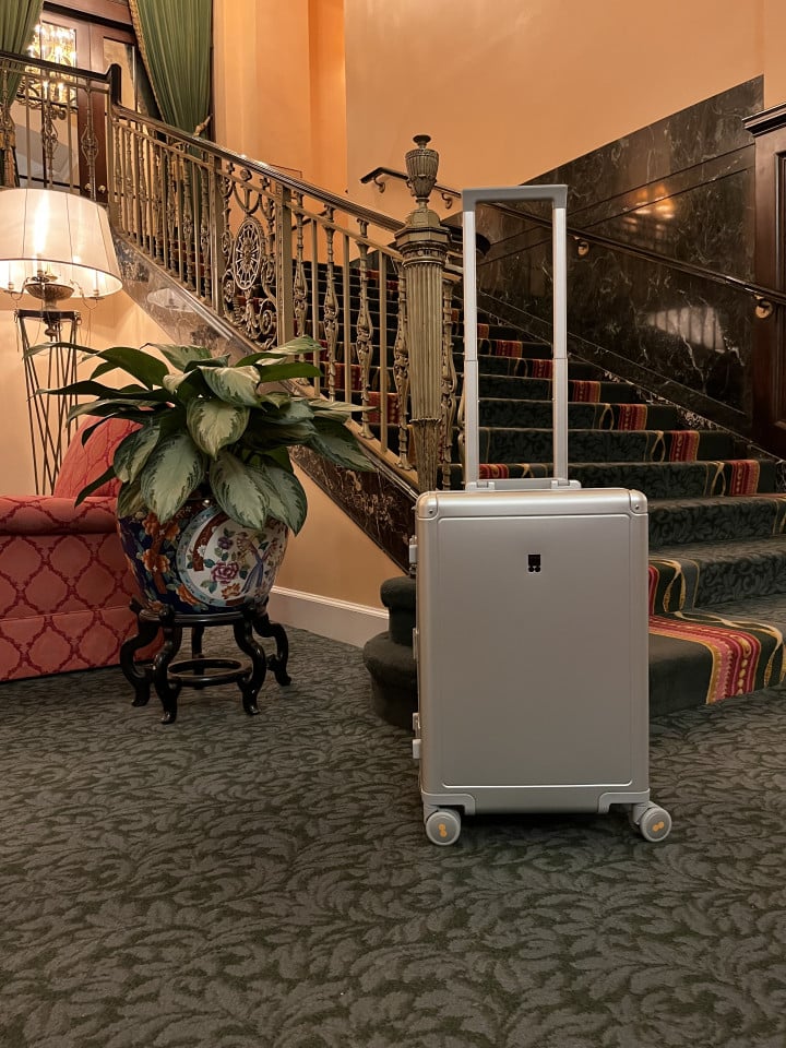 Level8 Gibraltar aluminum carry-on standing in hotel lobby with extended handle