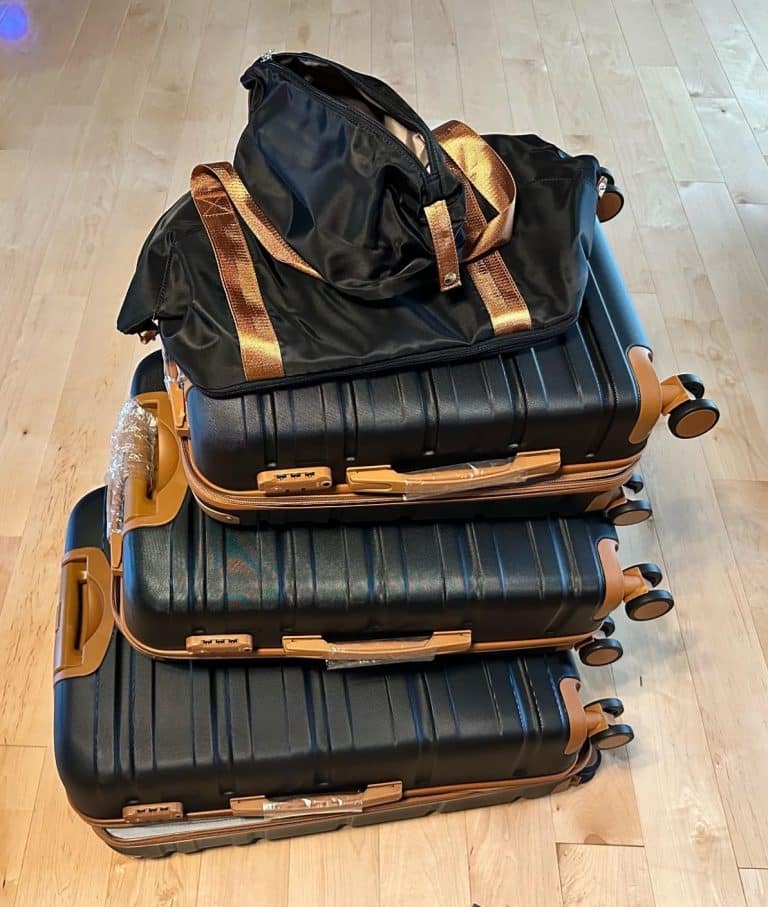 Three TAKUMI suitcases stacked together with the matching duffle bag placed on top.