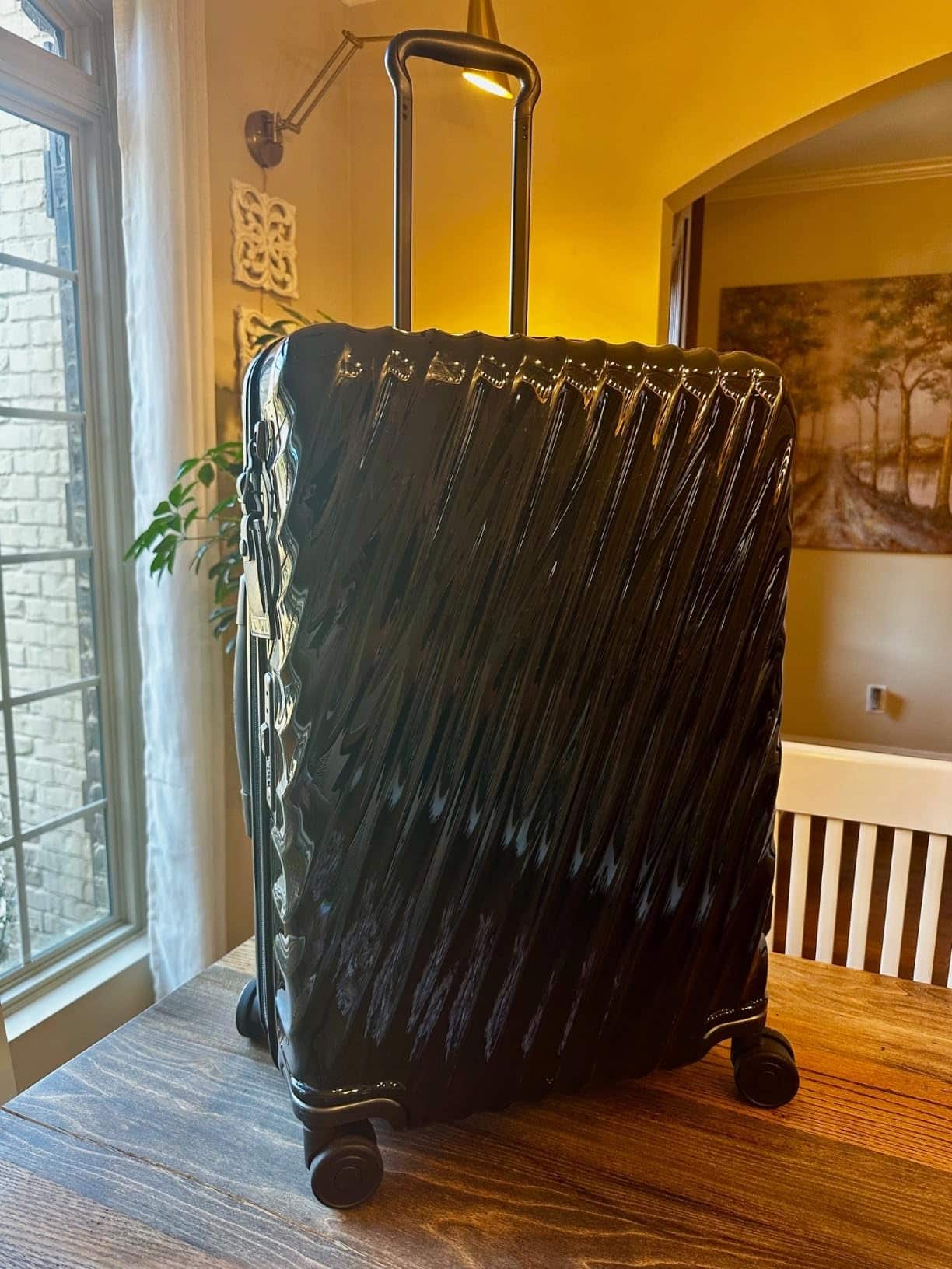 TUMI 19 Degree Checked Luggage photographed indoors under warm lighting, highlighting the glossy finish and textured ridges.