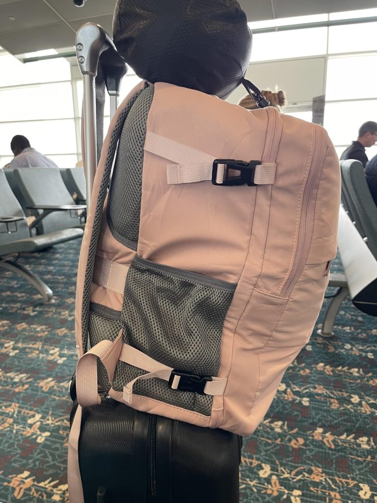 Taygeer Travel Backpack for Women Review 5 Taygeer Travel Backpack secured on top of a suitcase using its luggage strap at the airport.