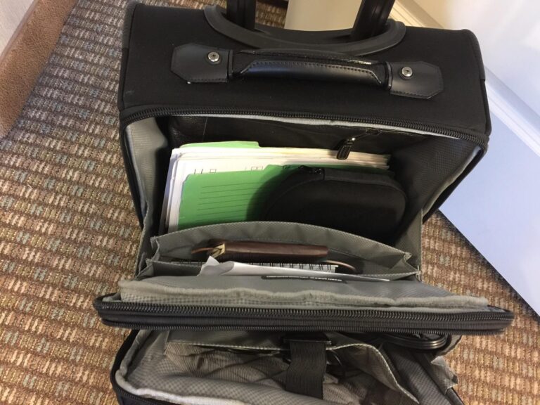 rolling travel briefcase with wheels open showing organized compartments with documents, folders, and accessories