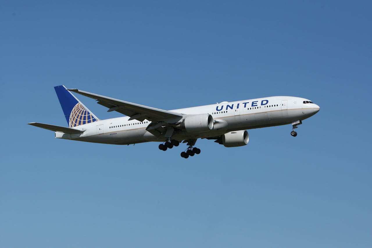 United Airlines passenger airplane flying in clear blue sky during approach for landing