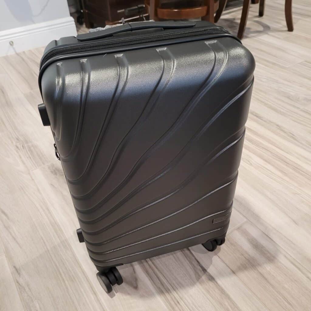 VANKEAN Carry On Luggage Review: Lightweight, Durable & Airline-Friendly Spinner Suitcase 5 VANKEAN carry on luggage with spinner wheels in dark gray hard shell design, featuring textured polycarbonate exterior and 360-degree wheels on wooden floor