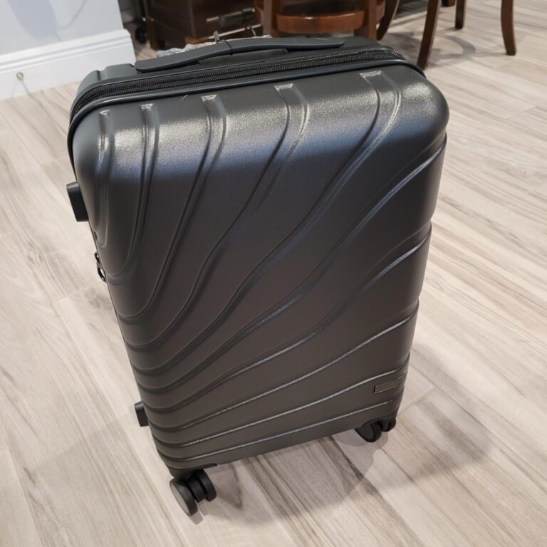 VANKEAN carry on luggage with spinner wheels in dark gray hard shell design, featuring textured polycarbonate exterior and 360-degree wheels on wooden floor