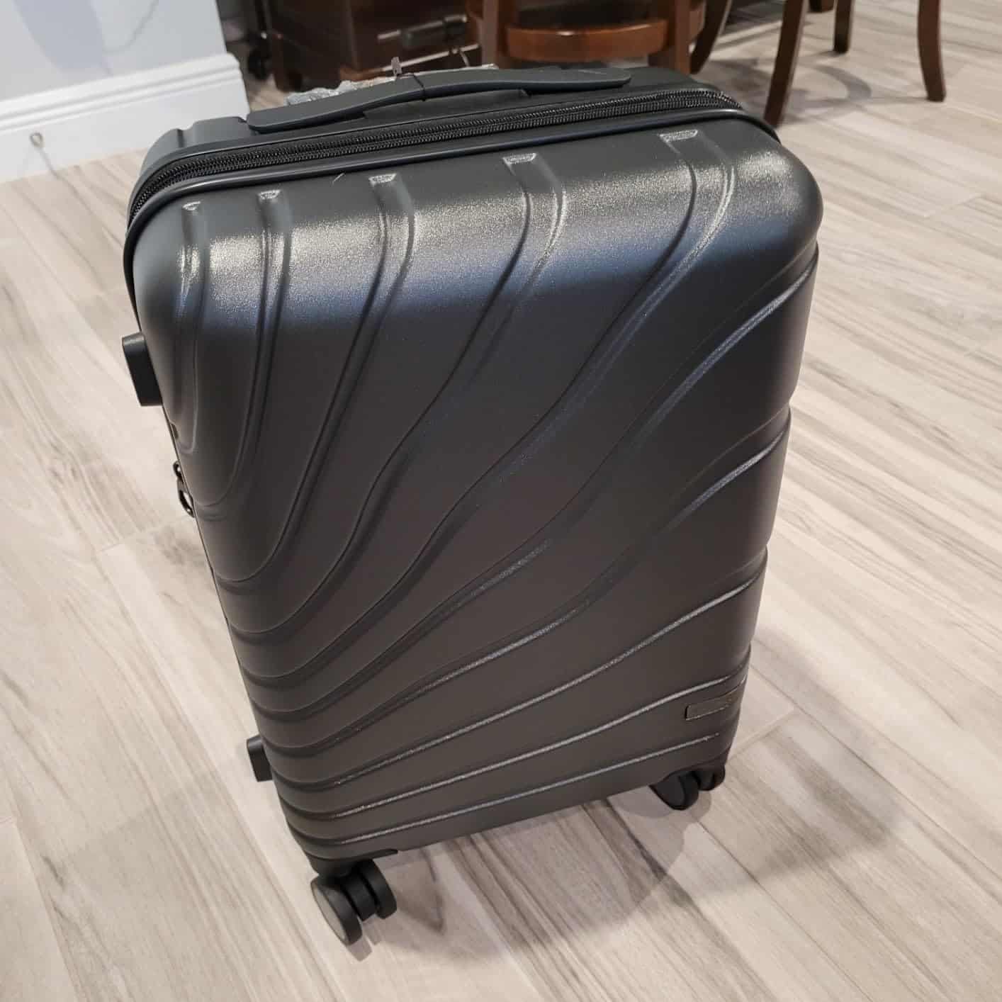 VANKEAN carry on luggage with spinner wheels in dark gray hard shell design, featuring textured polycarbonate exterior and 360-degree wheels on wooden floor