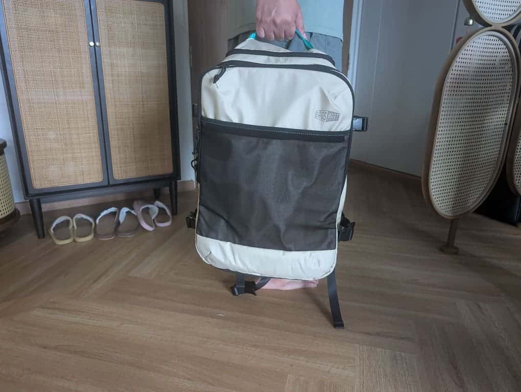 BAGSMART Blast Pro 40L Travel Backpack Review: A Surprisingly Smart Carry-On for One-Week Trips 7 Traveler holding the Blast Pro 40L backpack by the top grab handle inside a home