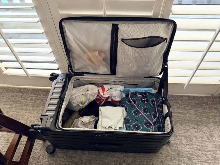 CENSIEN top-opening hard shell luggage packed with clothes and travel essentials beside a window in a bright living room