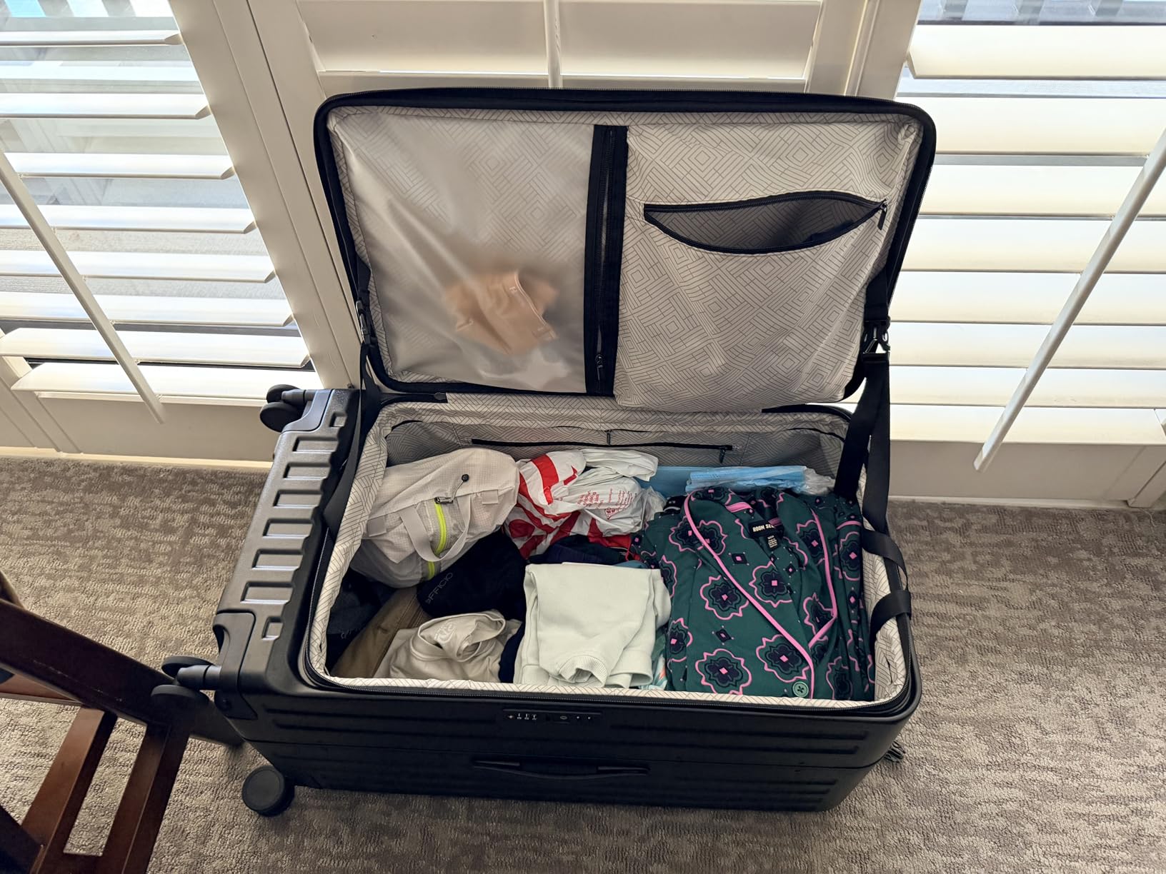 CENSIEN top-opening hard shell luggage packed with clothes and travel essentials beside a window in a bright living room