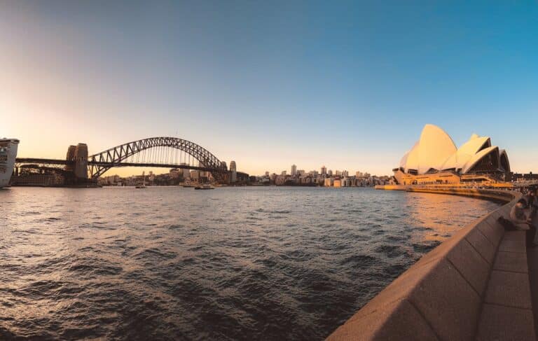Sydney Harbour at sunset with the Sydney Opera House and Harbour Bridge overlooking the water