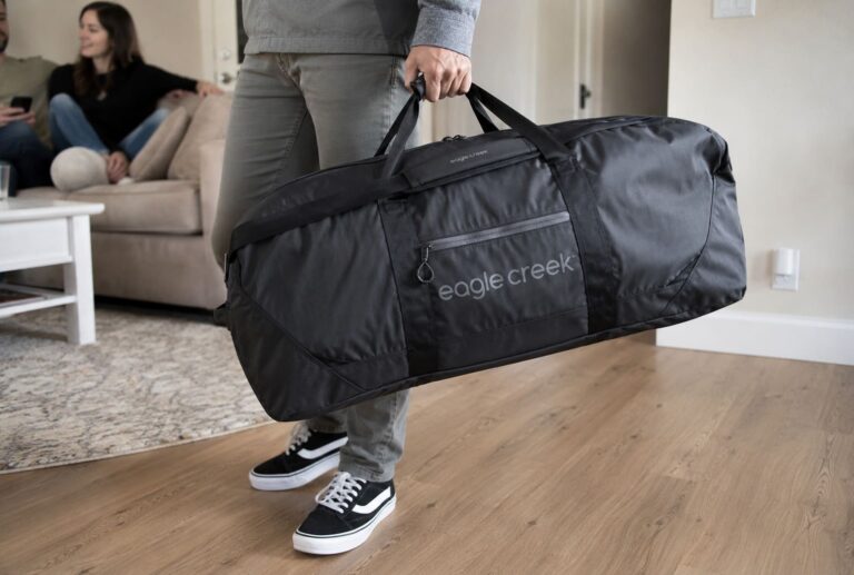 Traveler carrying the Eagle Creek No Matter What Duffel Bag in a living room before a trip, showcasing the bag's large capacity and durable design.