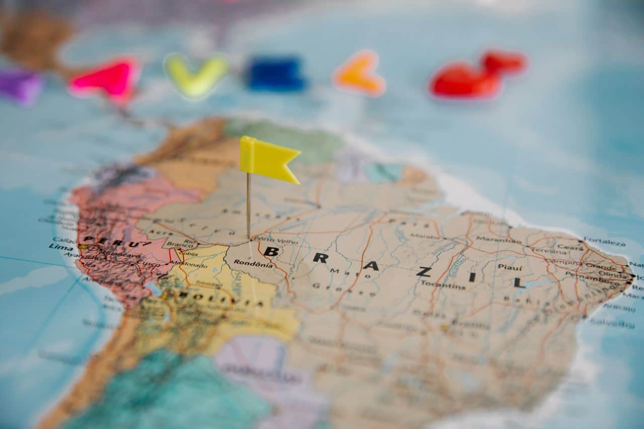 Map of South America with colorful location markers and a yellow flag pinned over Brazil, symbolizing travel planning and multi-country exploration across Latin America.