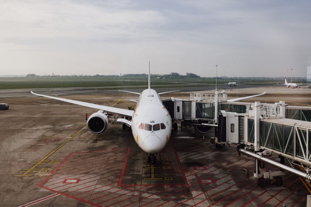 Passenger jet parked at an airport gate beside a jet bridge on a cloudy day