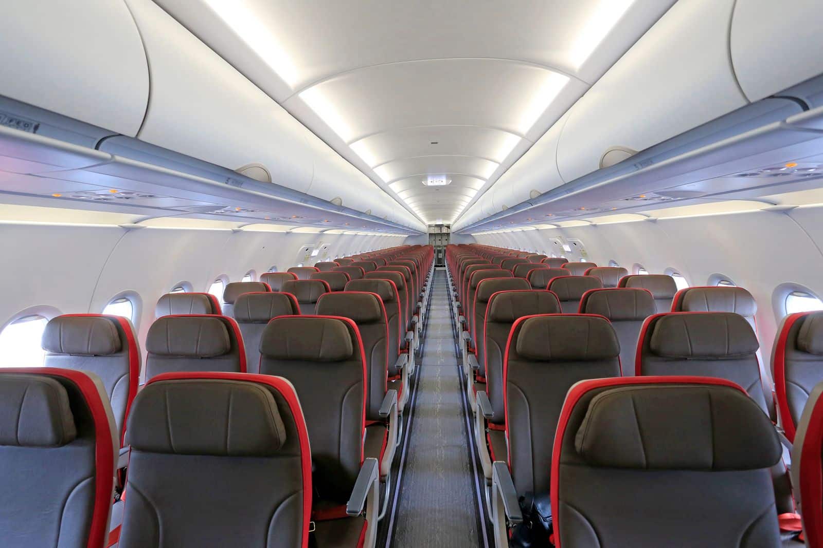 Empty aircraft cabin with rows of seats where underseat bags are stored